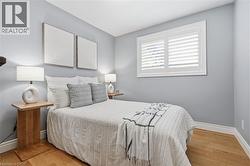 Wood-finish flooring with white baseboards, a window with plantation shutters, and light blue wall tones -