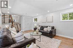 Recessed lighting, wood-finish flooring, light gray walls, white trim, and a contemporary open-riser staircase with wood treads and metal balusters -
