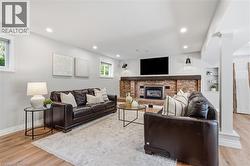 Brick fireplace with a substantial wood mantel, recessed lighting, wood-finish flooring, two windows, and built-in shelving -