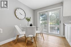Sliding glass door, wood-finish flooring, white baseboards, light grey wall finish, white cabinetry -
