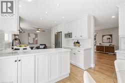 Kitchen featuring white Shaker-style cabinetry, white countertops, subway tile backsplash, and stainless steel appliances -