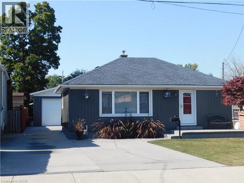 Gray siding exterior with white trim, a dark shingled roof, and an attached garage with a white door - 625 Tate Avenue, Hamilton, ON 