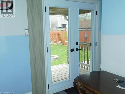 New Glass-paneled double doors open to an exterior wood deck, featuring a fenced yard with a fire pit - 625 Tate Avenue, Hamilton, ON 
