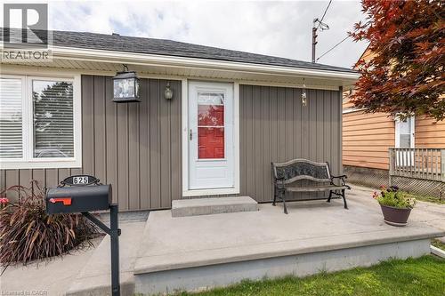 Exterior featuring vertical panel siding, a red entry door, a concrete porch, and a dedicated mailbox - 625 Tate Avenue, Hamilton, ON 