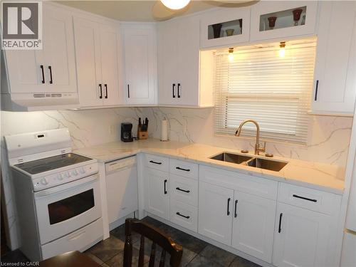 White cabinetry with black hardware, stone-finish countertops, dual basin stainless steel sink, stainless steel faucet, and tile flooring - 625 Tate Avenue, Hamilton, ON 