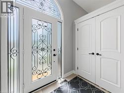 Entryway featuring an ornate glass-paneled door with wrought iron detailing, a matching transom window, and tiled flooring - 