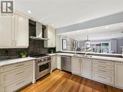 Hardwood flooring, stainless steel range with hood, granite countertops, tile backsplash, and recessed lighting - 