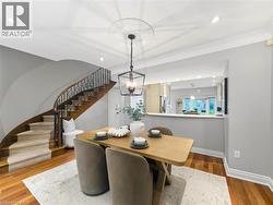 Hardwood flooring, curved staircase with wrought iron railing, recessed lighting, crown molding, and a kitchen pass-through with a breakfast bar - 
