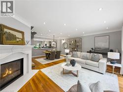 Spacious open-concept living area featuring a built-in fireplace with a decorative mantel, wood-finish flooring, recessed lighting, and crown molding - 