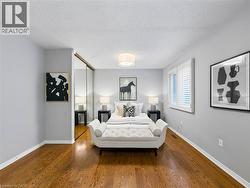 Hardwood flooring, light gray wall finishes, white window shutters, ceiling-mounted light fixture, and mirrored closet doors - 