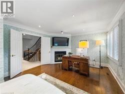 Hardwood flooring, fireplace with white brick surround, white plantation shutters, decorative wallpaper, and crown molding - 
