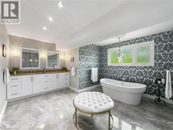 Freestanding soaking tub, dual vanity with wood-finish countertop, patterned accent wall, recessed lighting, and large format floor tiles - 