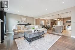 Recessed lighting, wood-finish flooring, island with pendant lighting, stainless steel appliances, and a staircase with wood treads - 