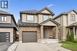 Modern two-story home featuring a brick and siding exterior with peaked roofline, double-car garage with dark paneled doors, and a welcoming front entrance with stone accents and concrete driveway - 