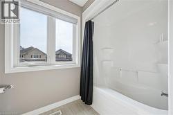 Double-pane window with roller blind, white bathtub, and integrated shower surround - 