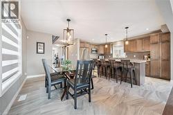 Open-concept kitchen and dining area featuring wood cabinetry, an island with seating, pendant lighting, and light-toned tile flooring - 