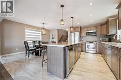 Gourmet kitchen featuring stainless steel appliances, a center island with a beverage refrigerator, and tile flooring - 