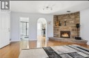 Corner stone-clad fireplace with hearth, wood-finish flooring, and white interior doors - 85 Summerlea Drive, Hamilton, ON 