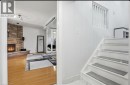 Stone-clad fireplace feature with a raised hearth, wood-finish flooring, white painted staircase, and white baluster railing - 85 Summerlea Drive, Hamilton, ON 