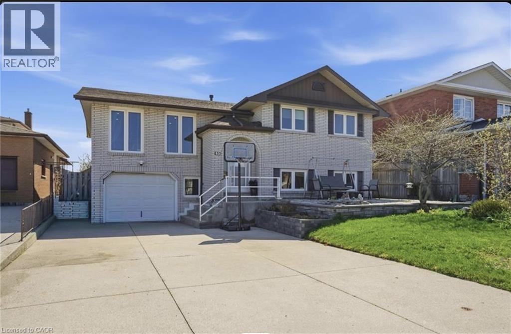 Two-story residence featuring light-colored brick exterior, attached garage, and paved driveway - 85 Summerlea Drive, Hamilton, ON