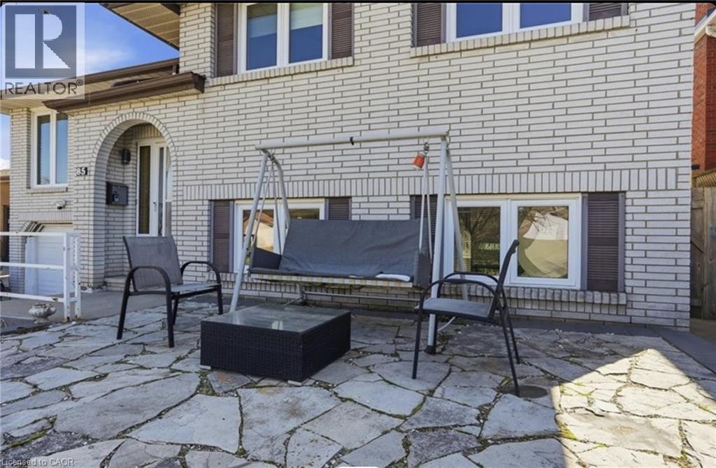 Stone patio with irregular flagstones, brick exterior, arched entryway, and white-framed windows - 85 Summerlea Drive, Hamilton, ON