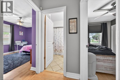 Wood-finish flooring throughout the hallway, leading to rooms featuring ceiling fans and windows - 420 Upper Gage Avenue, Hamilton, ON 