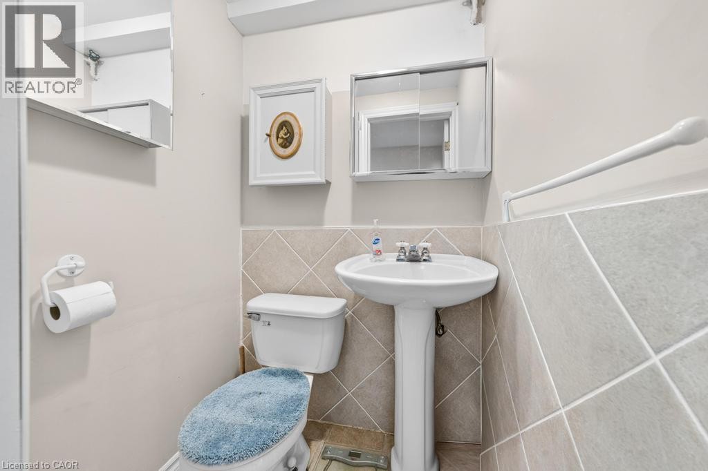 Pedestal sink with chrome faucet, ceramic toilet, and wall-mounted medicine cabinet - 420 Upper Gage Avenue, Hamilton, ON