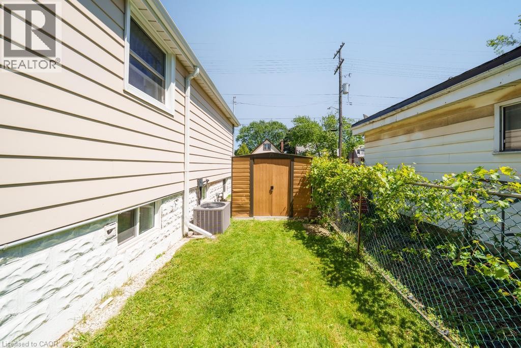 Grassed side yard with a wood-sided storage shed and chain-link fencing - 420 Upper Gage Avenue, Hamilton, ON