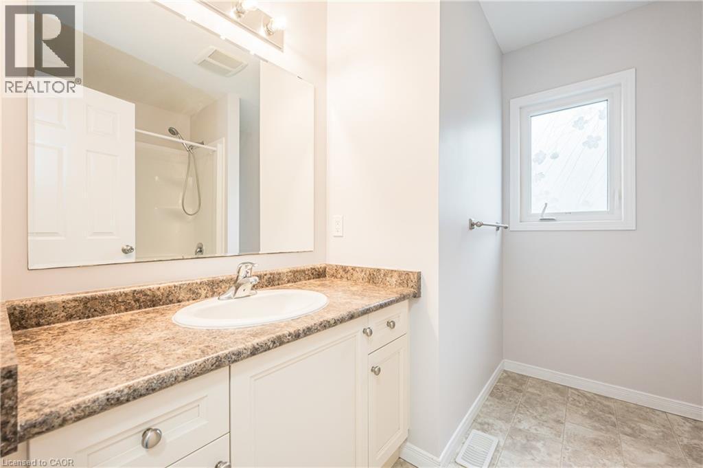 Vanity with a laminate countertop and integrated sink, chrome faucet, wall-mounted mirror, and tile flooring - 224 Jessica Crescent Unit# B, Kitchener, ON