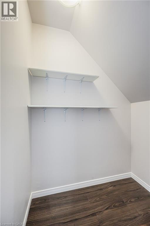 Angled ceiling storage area with two white shelves, wood-finish flooring, and white wall paint - 224 Jessica Crescent Unit# B, Kitchener, ON
