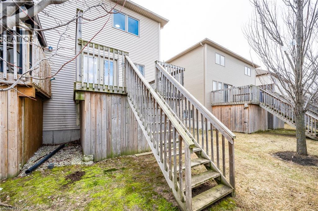 Rear exterior featuring light-toned siding, a wood deck with railings, and an exterior staircase - 224 Jessica Crescent Unit# B, Kitchener, ON