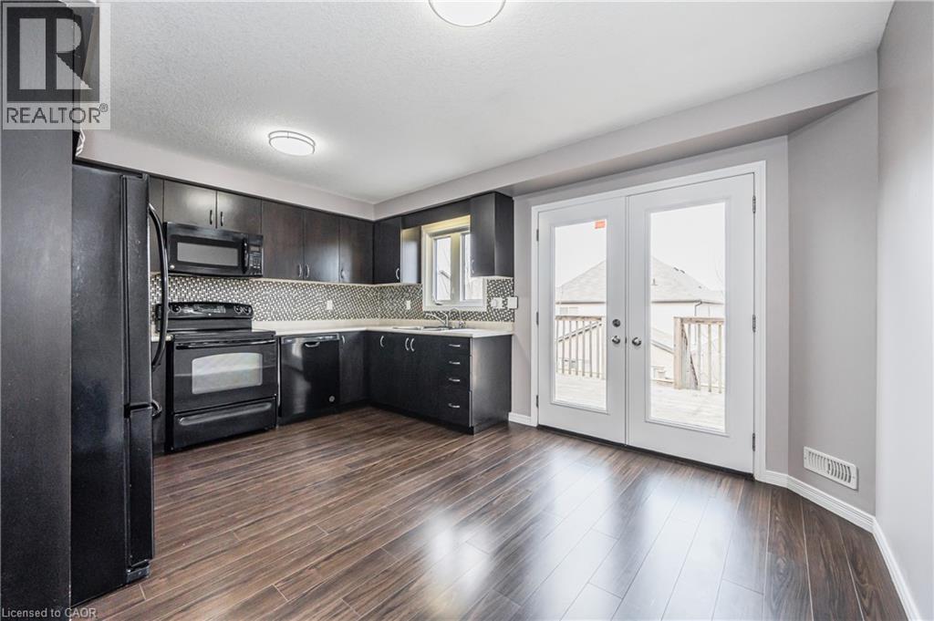 Kitchen with wood-finish flooring, dark cabinetry, and black appliances - 224 Jessica Crescent Unit# B, Kitchener, ON