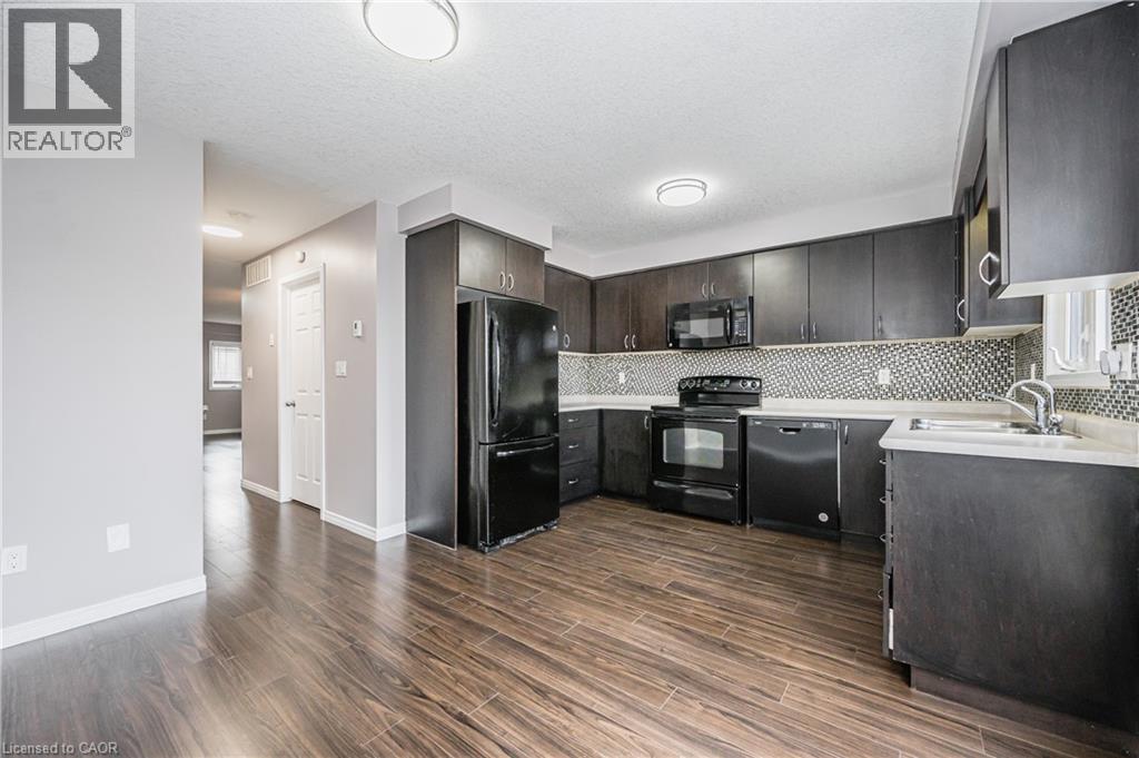 Kitchen featuring wood-finish flooring, dark cabinetry, and black appliances - 224 Jessica Crescent Unit# B, Kitchener, ON