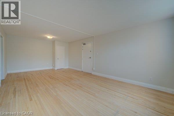 Light wood-finish flooring, recessed ceiling light fixture, white interior doors, and neutral wall paint - 141 Chapel Street, Kitchener, ON
