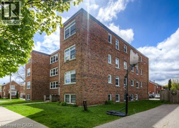 Brick exterior building with multiple windows and a manicured lawn - 141 Chapel Street, Kitchener, ON