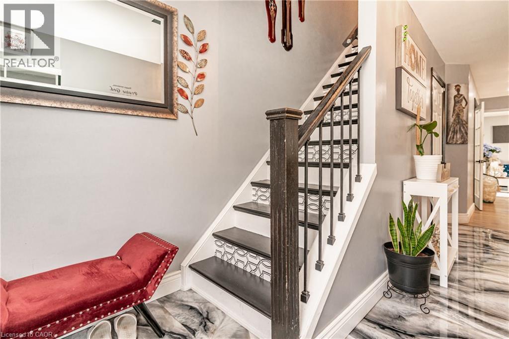 Two-tone staircase with black treads and patterned risers, dark wood newel post and railings, and metal balusters - 52 Charters Road, Brampton, ON