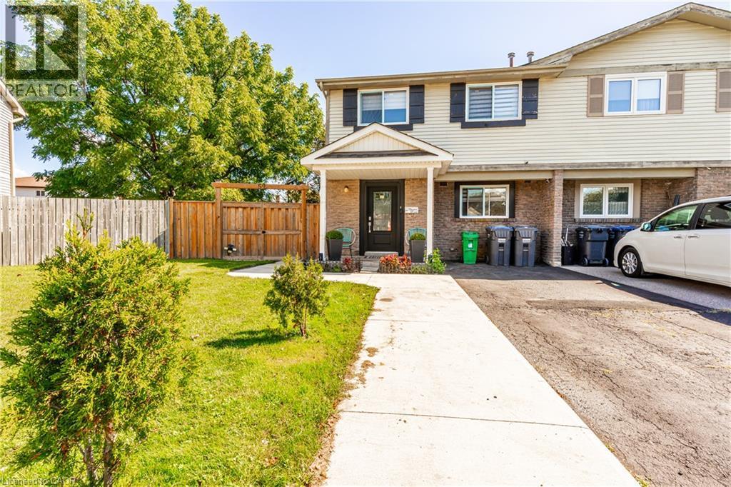Cream-colored siding exterior with dark shutters, brick facade, covered entry, and a paved driveway - 52 Charters Road, Brampton, ON