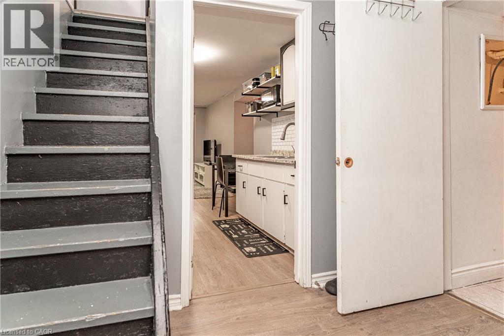 Wood-finish flooring, white cabinetry, subway tile backsplash, and light-toned countertops - 52 Charters Road, Brampton, ON