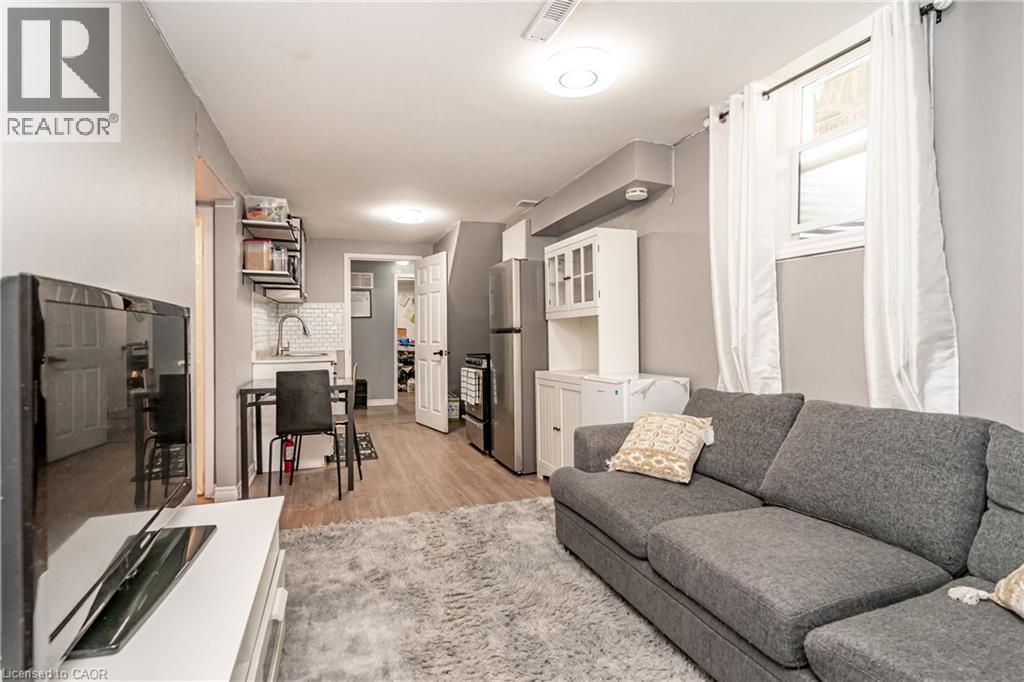 Open-concept living area with wood-finish flooring, a kitchen featuring a white subway tile backsplash, and stainless steel appliances - 52 Charters Road, Brampton, ON