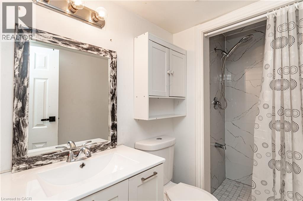 Vanity with an integrated rectangular sink, wall-mounted storage cabinet, and a shower with tile surround - 52 Charters Road, Brampton, ON