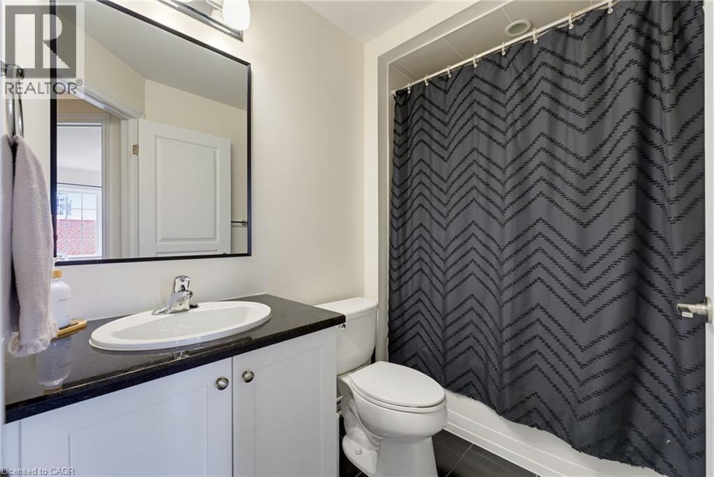 White vanity with dark countertop, undermount sink, and chrome faucet - 541 Winston Road Unit# 50, Grimsby, ON