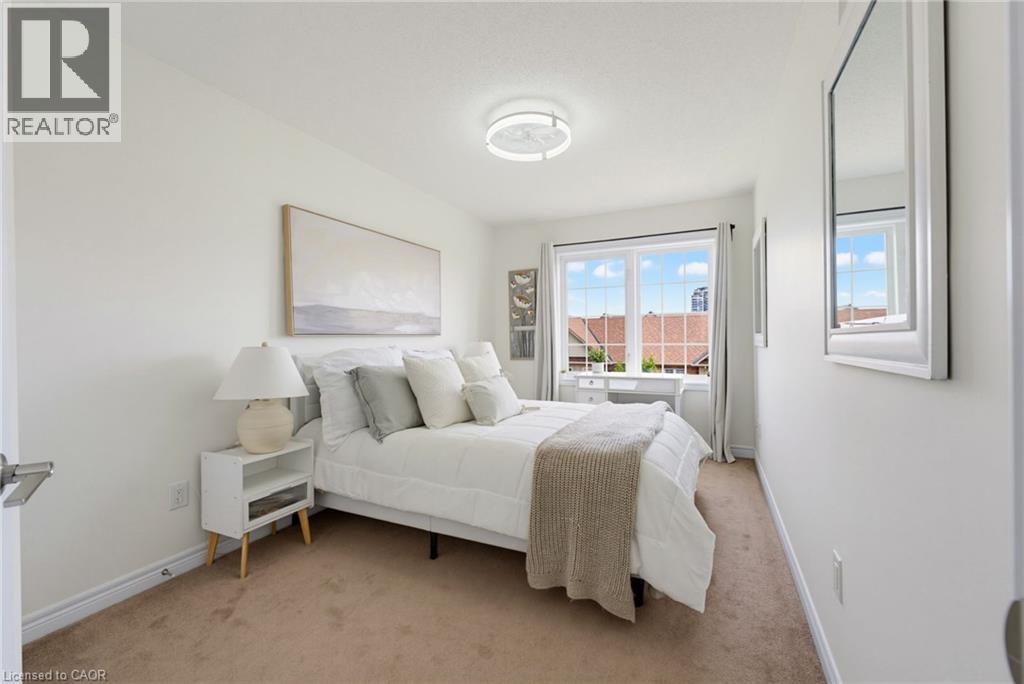 Bright bedroom featuring a large window with grid pattern, neutral-toned walls, and carpet flooring - 541 Winston Road Unit# 50, Grimsby, ON