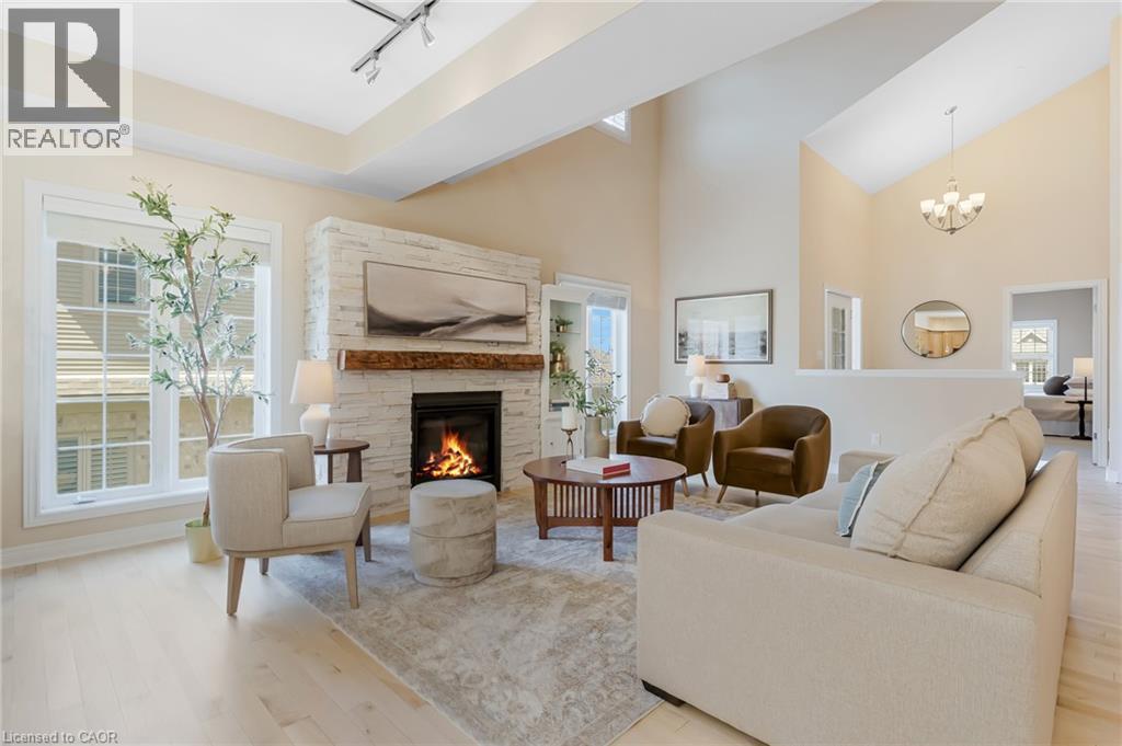Vaulted ceilings with a chandelier, light wood-finish flooring, and a stone-clad fireplace with a wood mantel - 227 Chestnut Hill Crescent, Kitchener, ON