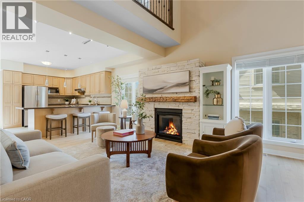Open-concept living space featuring a stacked stone fireplace with a substantial wood mantel, built-in display cabinetry, and a kitchen with stainless steel appliances - 227 Chestnut Hill Crescent, Kitchener, ON