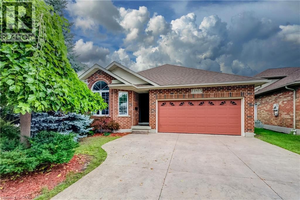 Brick exterior with an integrated garage, arched window, paved driveway, and mature landscaping - 245 Fern Crescent, Waterloo, ON