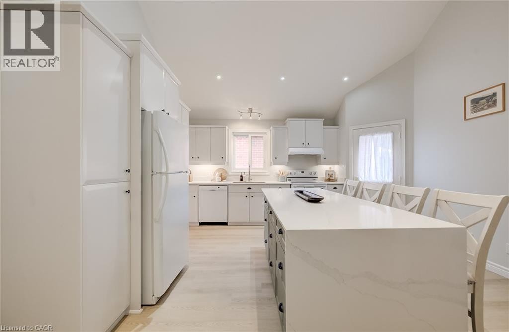Kitchen featuring white cabinetry, light wood-finish flooring, a central island with a light-toned countertop, and recessed lighting - 245 Fern Crescent, Waterloo, ON