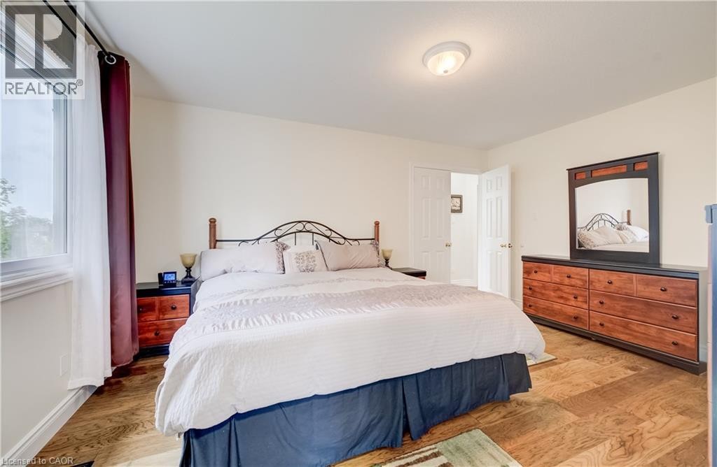 Wood-finish flooring with neutral wall tones, a large window, a ceiling-mounted light fixture, and a white interior door - 245 Fern Crescent, Waterloo, ON