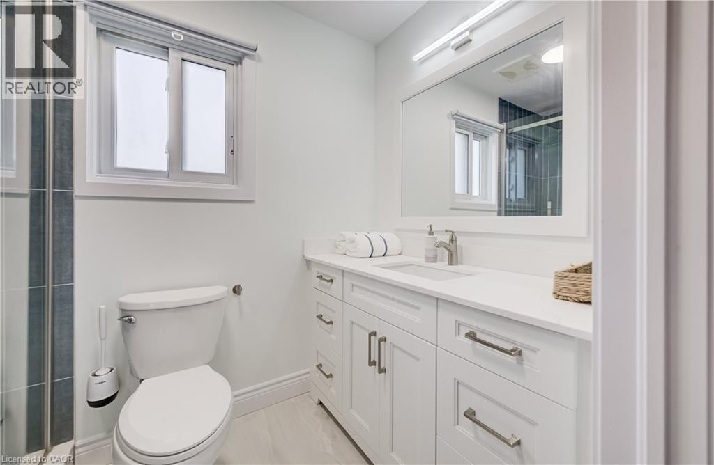 White vanity with shaker-style cabinetry, a single basin sink, and a rectangular mirror with integrated lighting - 245 Fern Crescent, Waterloo, ON