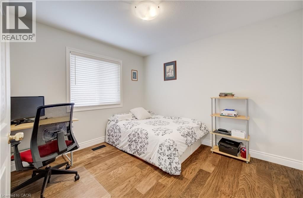 Light-filled room featuring wood-finish flooring, a white-framed window with horizontal blinds, and a flush-mount ceiling light - 245 Fern Crescent, Waterloo, ON