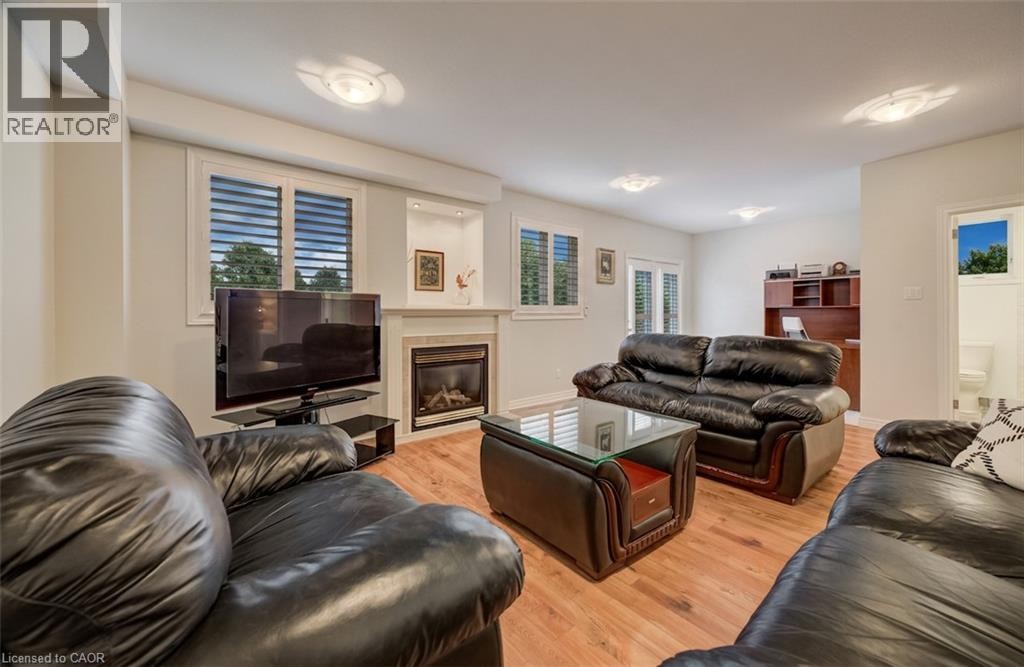 Living area featuring wood-finish flooring, a built-in fireplace with a mantel, recessed wall niches, and multiple windows with louvered blinds - 245 Fern Crescent, Waterloo, ON
